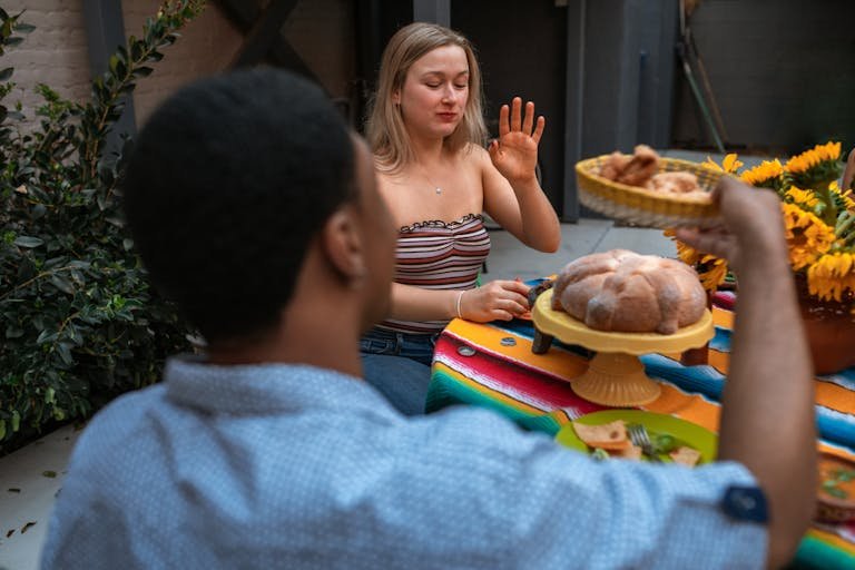 Two young friends enjoying a relaxed meal outdoors, sharing food and conversation.